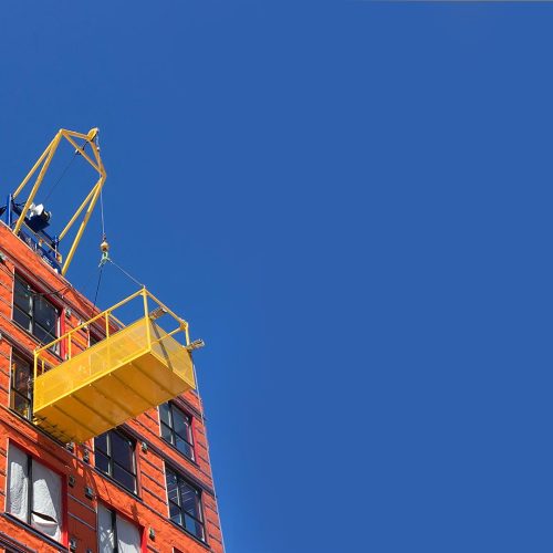 A DOC® Material Hoist installed on the roof of a 8-story building with a DOC® Material Basket attached. Trucks can be unloaded directly to the basket, and delivered to any floor of the building.